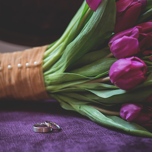 purple bouquet and wedding rings