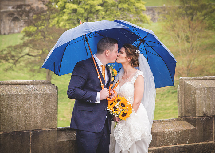 bride and groom in rain with blue umbrellas